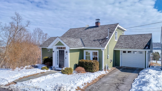 new england style home with a garage, driveway, and a chimney