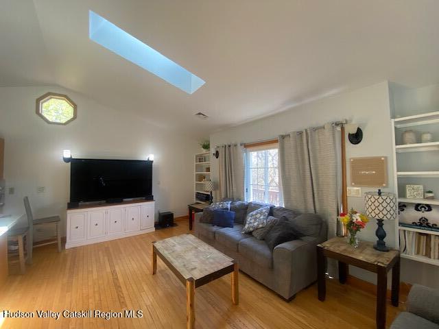 87 Dock St, Saugerties, NY 12477 - living room featuring wood finished floors, healthy amount of natural light, vaulted ceiling, and a skylight