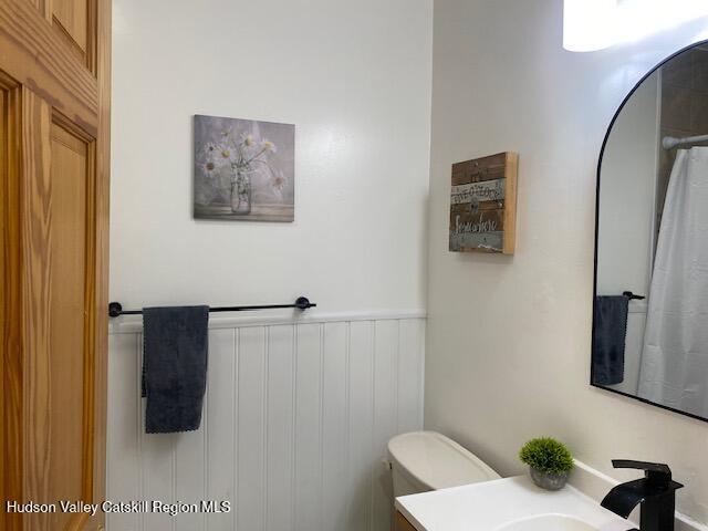 87 Dock St, Saugerties, NY 12477 - full bath featuring vanity, toilet, wainscoting, and a shower with curtain