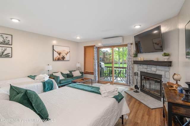 11 Quads Way, Windham, NY 12496 - bedroom featuring a wall unit AC, access to exterior, wood finished floors, a stone fireplace, and recessed lighting
