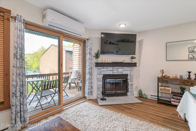 11 Quads Way, Windham, NY 12496 - living room featuring a wall unit AC, a stone fireplace, and wood finished floors