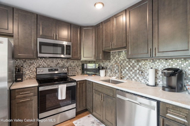 11 Quads Way, Windham, NY 12496 - kitchen featuring appliances with stainless steel finishes, a sink, dark brown cabinets, decorative backsplash, and light stone countertops