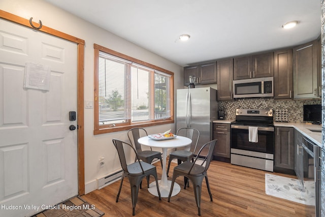 11 Quads Way, Windham, NY 12496 - kitchen featuring appliances with stainless steel finishes, a baseboard radiator, light countertops, light wood-style floors, and tasteful backsplash