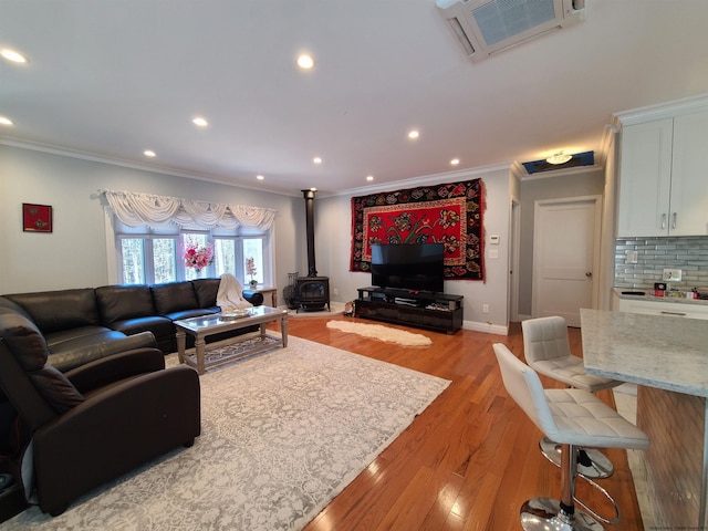 living room with light hardwood / wood-style floors, a wood stove, and ornamental molding