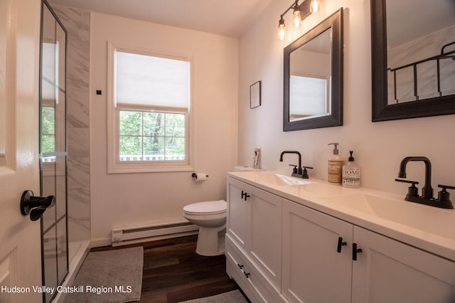 bathroom featuring vanity, wood-type flooring, a baseboard heating unit, and tiled shower