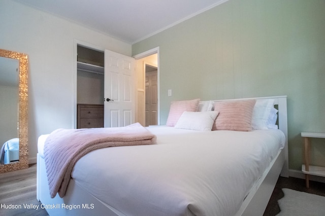 bedroom featuring hardwood / wood-style flooring, crown molding, and a closet