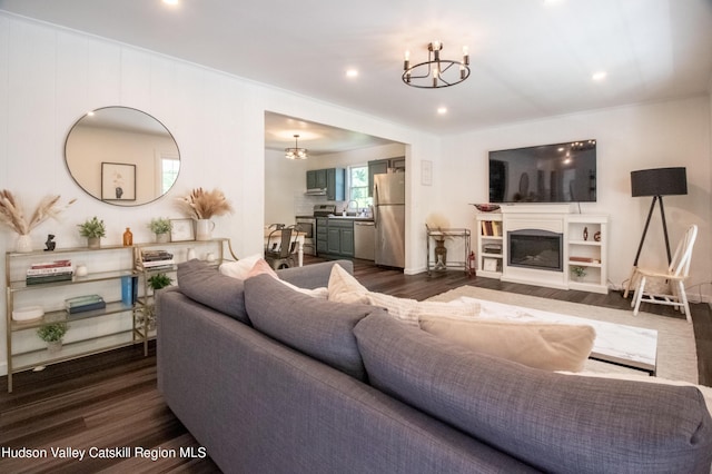 living room with dark hardwood / wood-style flooring, a notable chandelier, and sink