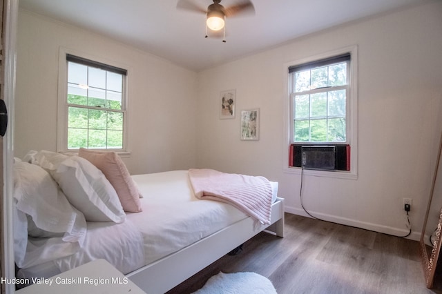 bedroom with cooling unit, ceiling fan, and dark hardwood / wood-style flooring