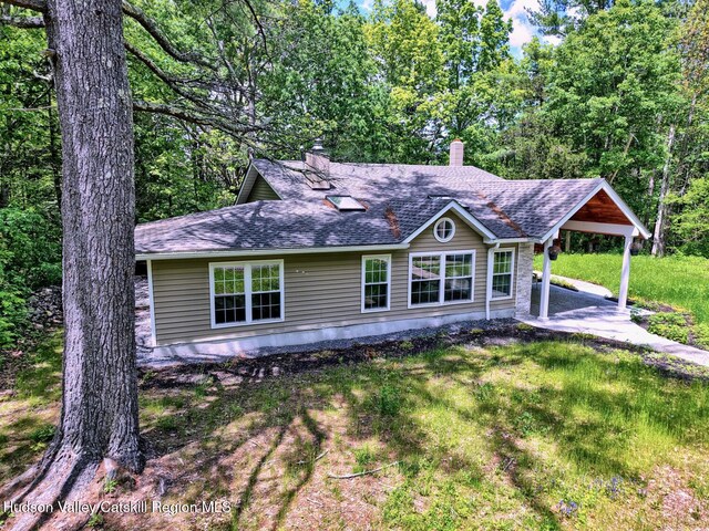 534 Rte 145, Cairo, NY 12413 - view of front facade featuring a chimney, a carport, a shingled roof, and a front lawn
