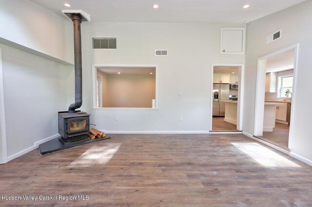 534 Rte 145, Cairo, NY 12413 - unfurnished living room featuring a wood stove, recessed lighting, wood finished floors, a high ceiling, and baseboards