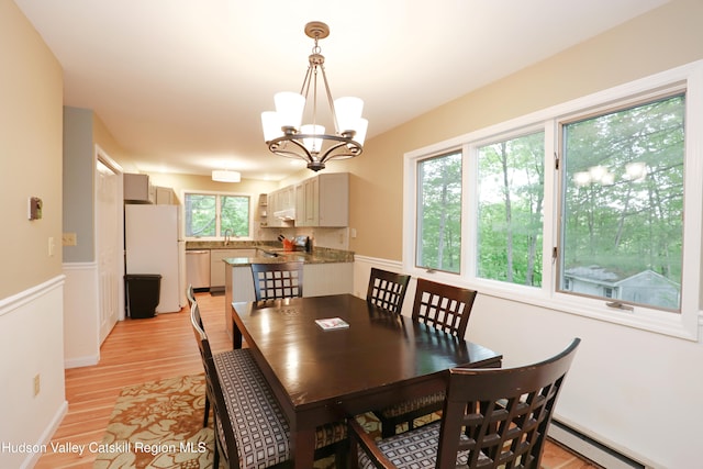 3 Carriage House Ct, Hyde Park, NY 12538 - dining area with baseboard heating, a chandelier, light wood-style floors, and a wainscoted wall