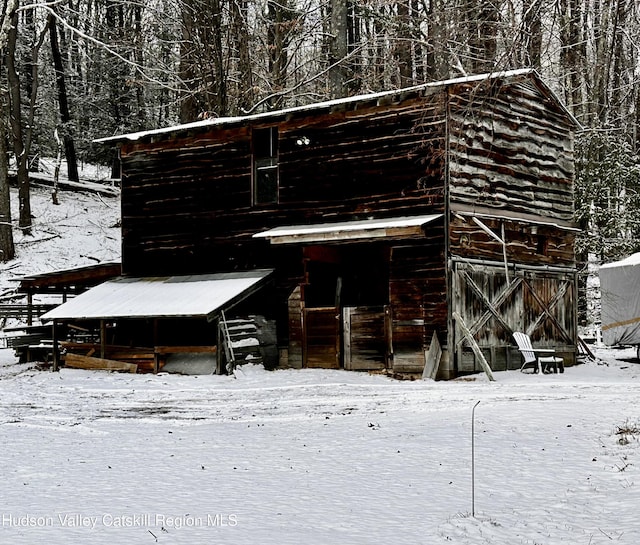 snow covered back of property featuring an outdoor structure