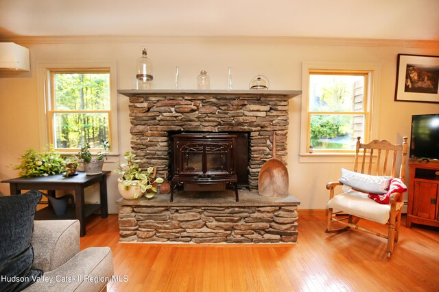 sitting room featuring hardwood / wood-style flooring, a stone fireplace, a wall mounted AC, and crown molding