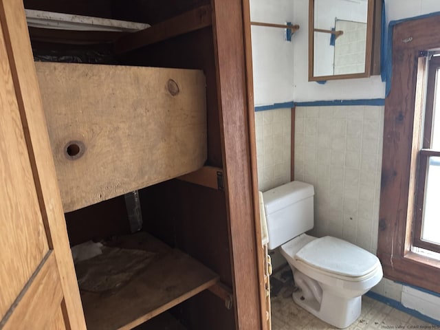 bathroom with toilet and tile walls