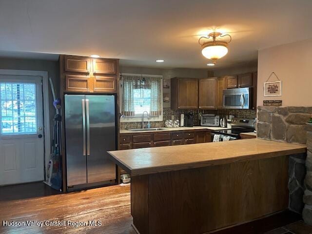 kitchen featuring stainless steel appliances, a peninsula, a sink, healthy amount of natural light, and recessed lighting