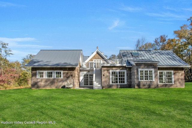 rear view of house featuring metal roof, a yard, and a standing seam roof