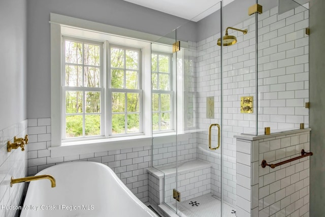 bathroom featuring plenty of natural light, independent shower and bath, and tile walls