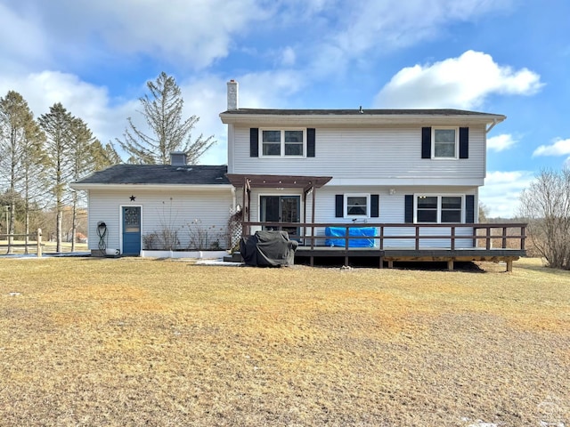 back of property featuring a deck, a chimney, and a yard