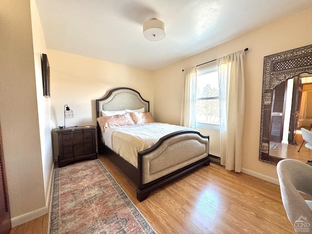 bedroom with wood finished floors, baseboards, and a baseboard radiator