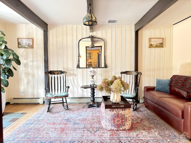 living area with a baseboard radiator, wood finished floors, and beam ceiling