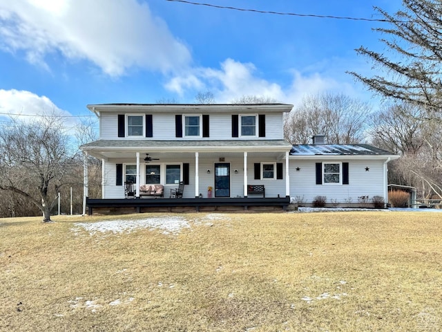 view of front of home with covered porch, a front lawn, a chimney, and ceiling fan