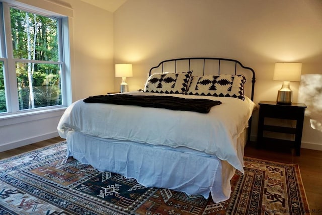 bedroom with baseboards, wood finished floors, and lofted ceiling
