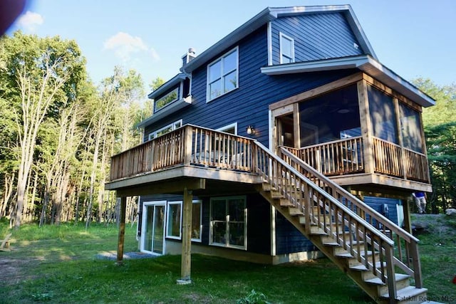 rear view of house with a chimney, a lawn, a deck, a sunroom, and stairs