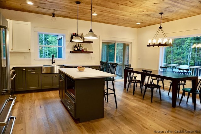 kitchen featuring a kitchen bar, light countertops, wooden ceiling, a sink, and light wood finished floors
