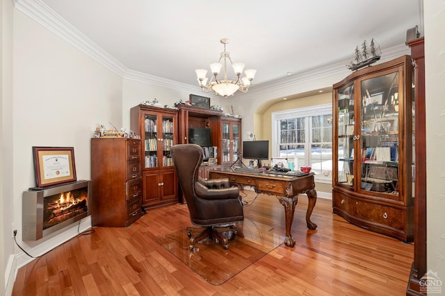home office with a chandelier, crown molding, light wood-type flooring, and a lit fireplace