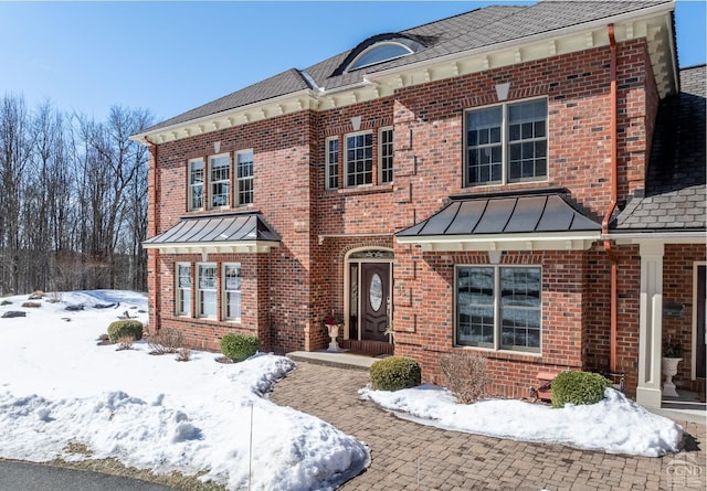 view of front facade with a standing seam roof, brick siding, and metal roof