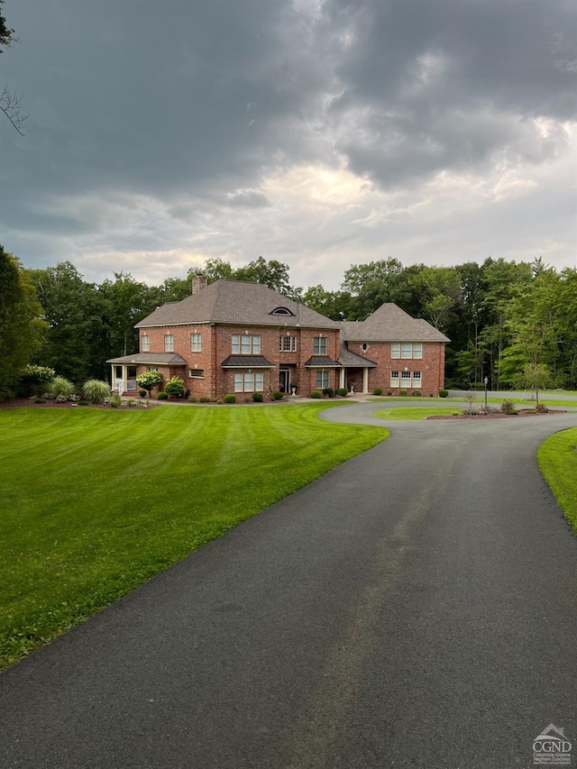view of front of property featuring brick siding, driveway, and a front lawn