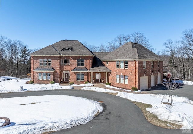 colonial home featuring driveway, a garage, and brick siding