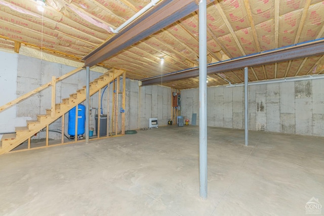unfinished basement featuring a water pressure tank and stairway