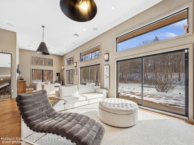 living room with recessed lighting, visible vents, light wood-style flooring, and a towering ceiling