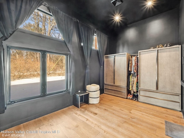 empty room with a high ceiling, visible vents, and light wood-style floors