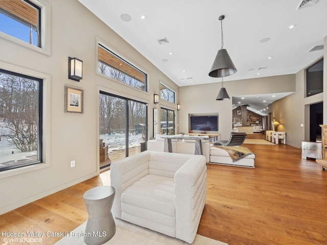 living room featuring a high ceiling, visible vents, light wood finished floors, and recessed lighting