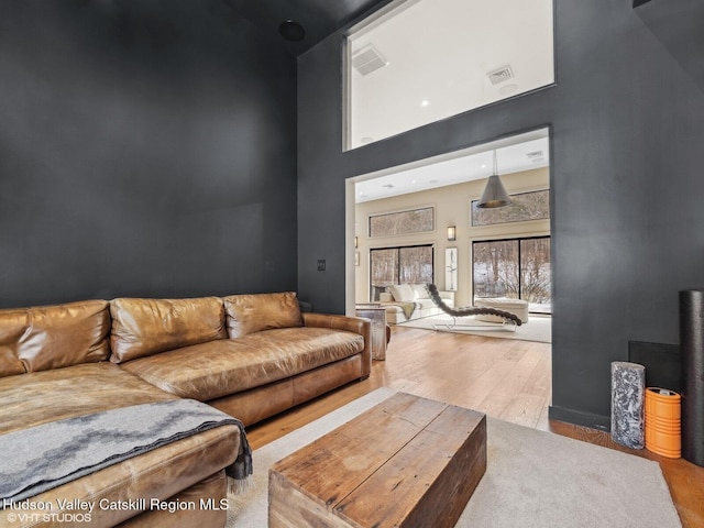 living room featuring visible vents, a towering ceiling, and light wood-style floors