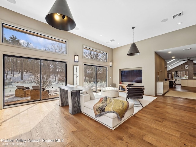 living area with a high ceiling, wood-type flooring, visible vents, and recessed lighting