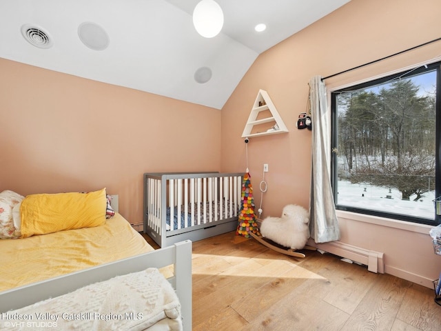 bedroom with vaulted ceiling, multiple windows, wood finished floors, and visible vents