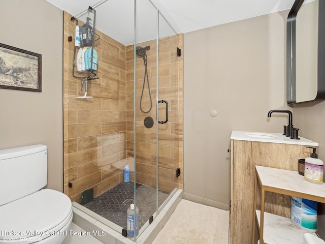 full bath with toilet, a shower stall, baseboards, and vanity