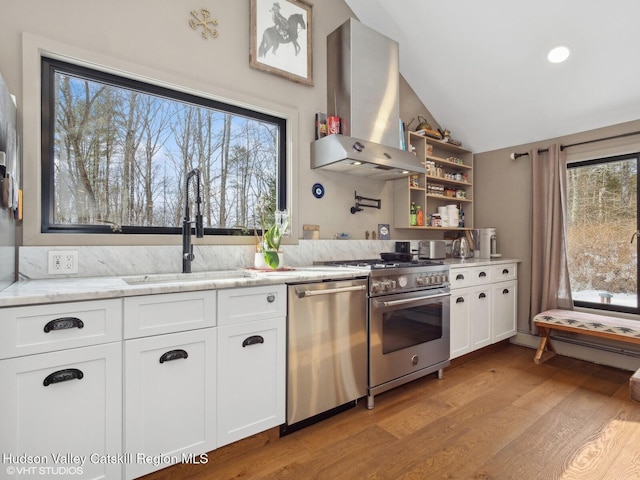 kitchen with white cabinets, appliances with stainless steel finishes, light stone countertops, extractor fan, and a sink