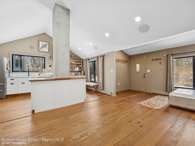 kitchen with light wood-style flooring, white cabinets, open floor plan, vaulted ceiling, and freestanding refrigerator