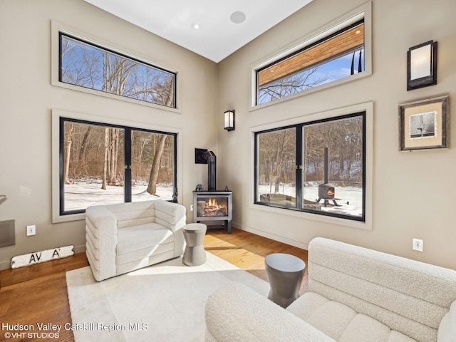 interior space with light wood-style flooring, a wood stove, and baseboards