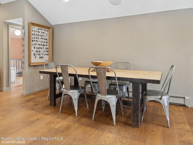 dining room featuring light wood-type flooring, vaulted ceiling, and baseboards