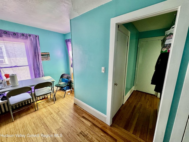 interior space featuring a textured ceiling, wood finished floors, and baseboards
