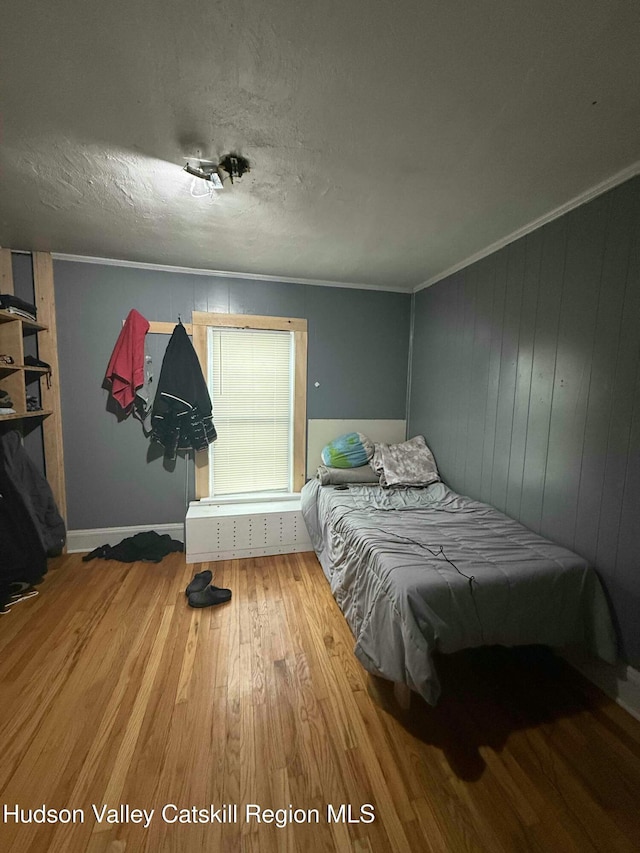 bedroom with crown molding, a textured ceiling, and wood finished floors