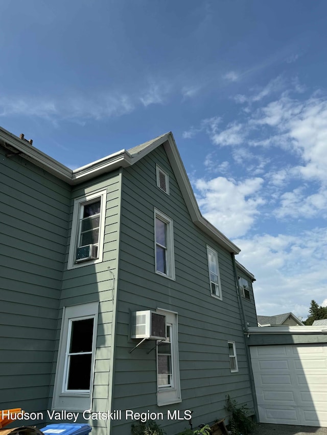 view of side of property featuring a garage and a wall unit AC