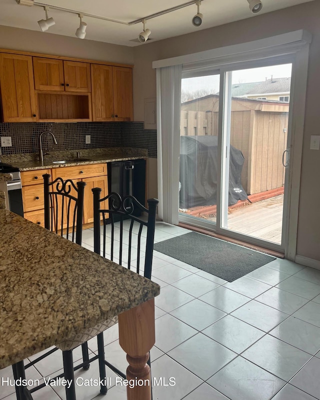 kitchen with dishwasher, light tile patterned flooring, decorative backsplash, stainless steel electric stove, and dark stone counters