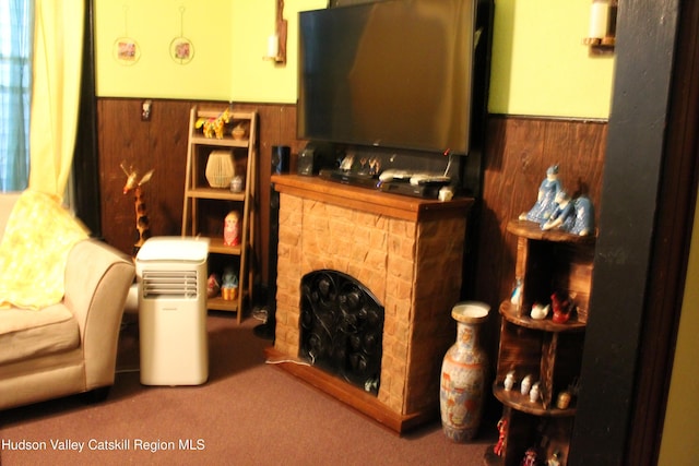 sitting room with wainscoting, wood walls, a fireplace, and carpet