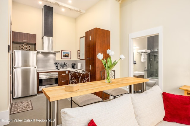 81 N Main St, Ellenville, NY 12428 - kitchen featuring modern cabinets, backsplash, stainless steel appliances, wall chimney range hood, and a towering ceiling